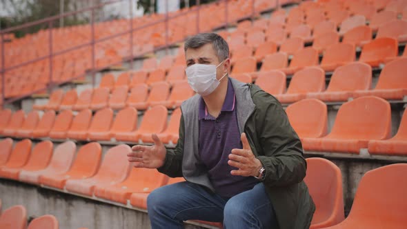 A Fan in a Medical Mask Sitting in an Empty Stadium is Emotionally Rooting for His Favorite Team