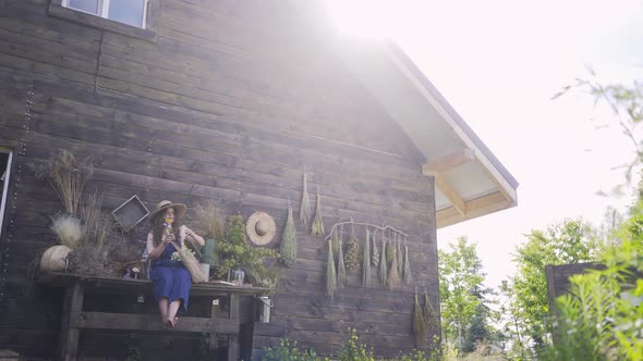 Young Lady in Hat Arranges Bouquet at Backyard