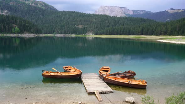 Tourist boats near wooden pier on Black lake in Montenegro, Europe alt