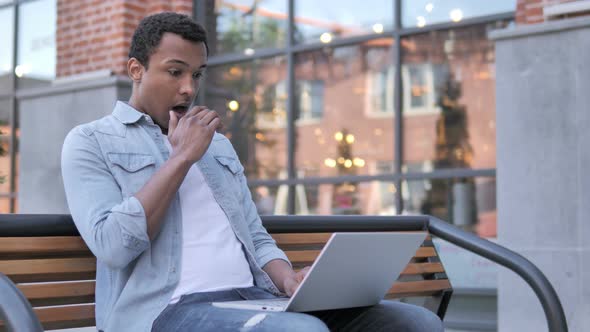 African Man in Shock while Working on Laptop Outdoor alt
