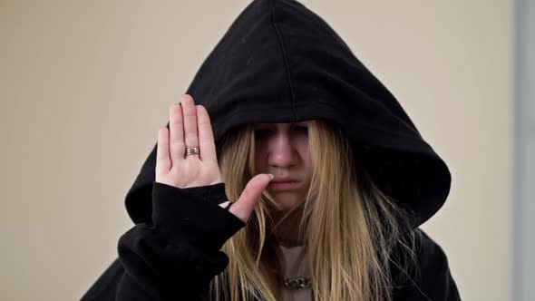 Teenage Girl Covering Her Face with a Hood Demonstrates a Gesture Indicating a Person's Need for