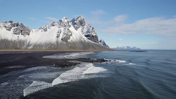 Flying above the coastline with stunning snow capped  Vestrahorn mountains rising up from the beach alt