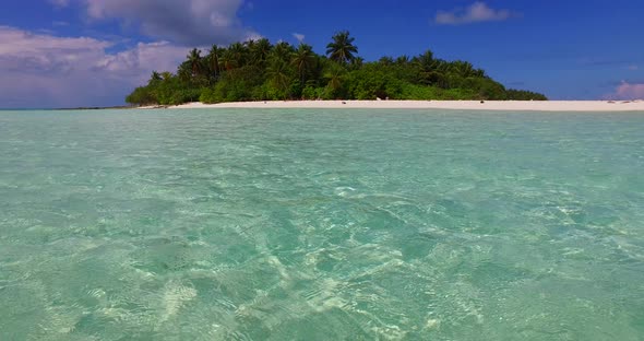 Natural fly over island view of a sandy white paradise beach and blue ocean background in hi res 4K alt