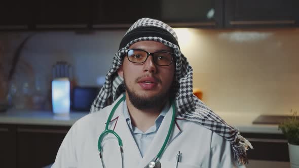 Arabic Doctor with Kandora and Glasses Giving Speech to the Camera From His Home Office