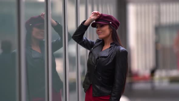 a Brunette with Long Hair in a Black Leather Jacket and a Burgundy Cap Leaned Elbow on the Glass alt