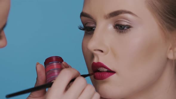 Make-up Applying on Beautiful Woman Face Isolated on Blue alt