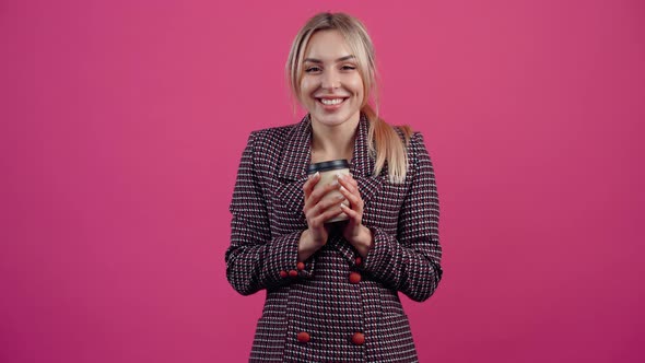 Happy Young Woman Holds a Cardboard Glass of Hot Coffee and Warms Up Smiling alt