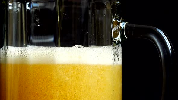 Pouring beer into a glass on a black background. alt