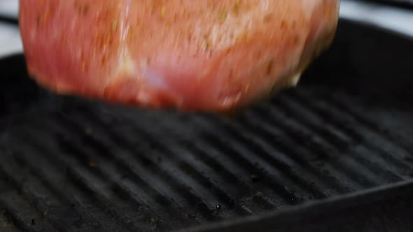 Turning Pork Meat On Grill Pan With Kitchen Pliers