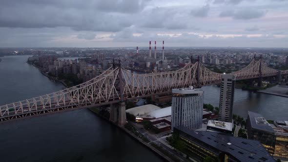 Aerial view away from the Queensboro Bridge, cloudy evening in NYC, USA - rotating, pull back, drone alt