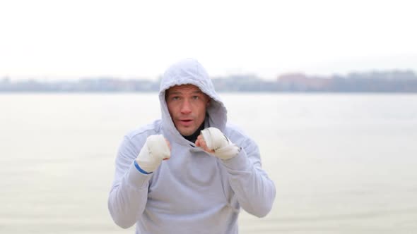 Boxing a man with an invisible opponent. A young man trains outdoors. alt