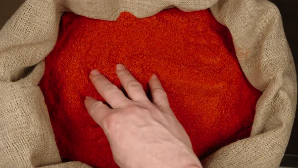 Male hand touching a red pepper powder in a sac
