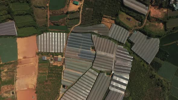 Top down drone shot of agricultural land featuring greenhouses and a village outside Dalat in the Ce alt