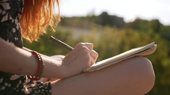 Redhead Young Girl Writing in Notepad on Laps Sitting in Black and White Dress in Slowmotion alt