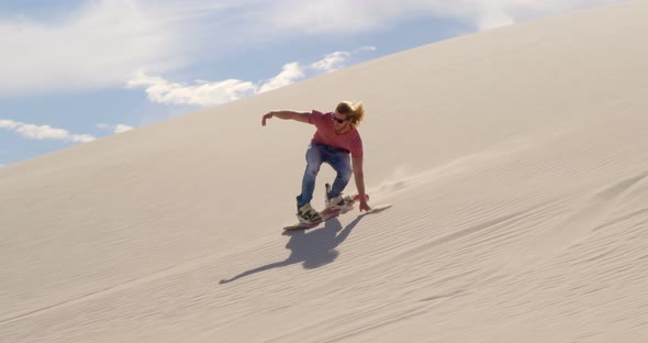 Man sand boarding on the slope in desert  alt