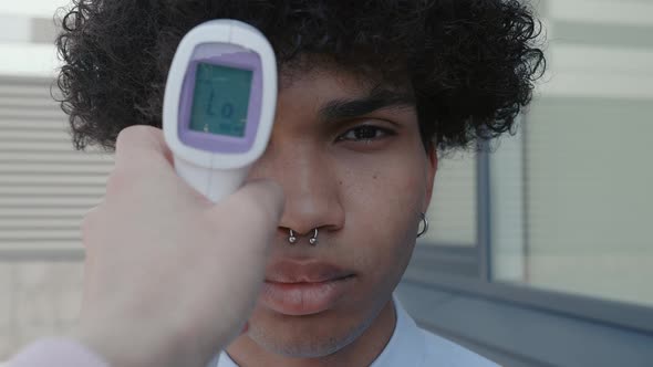 Closeup of a Doctor's Hand Female Holding a Noncontact Infrared Thermometer Over the Forehead of a alt