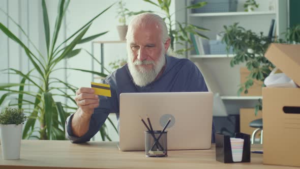 Successful Old Man Shopping Online From Home Using Laptop and Credit Card alt
