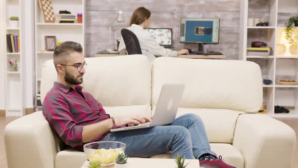 Handsome Freelancer Working on Laptop While Sitting on the Couch alt