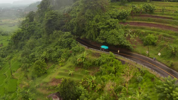 Aerial View of a Truck Driving on the Hill Road Past Farm Fields in Rural Countryside in Bali alt