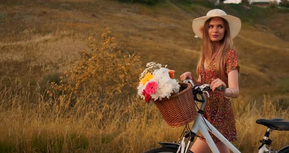 Middle Plan Girl in Dress Goes with Bike and Flowers in the Field alt