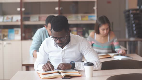 African American Male College Studen Preparing for Exams in the Library. alt