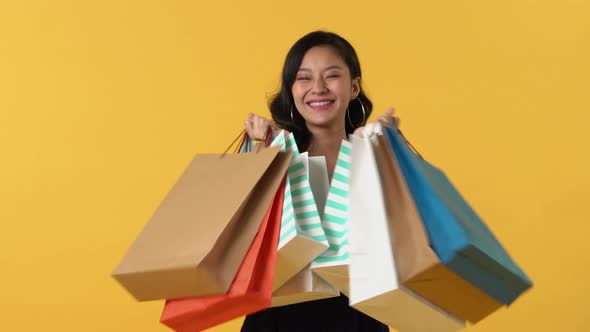 Excited surprised Asian woman carrying colorful shopping bags