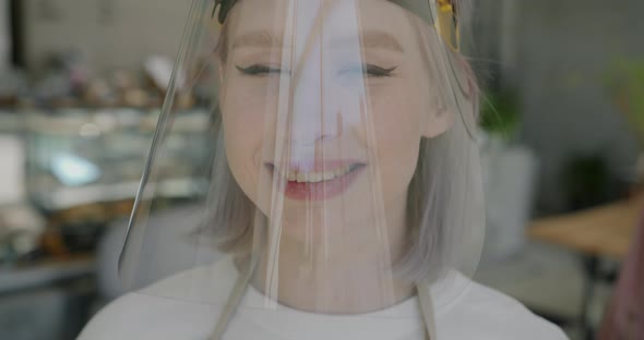 Portrait of Young Blonde Waitress Wearing Face Shield Standing in Cafe and Looking at Camera alt