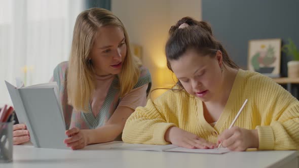 Girl with Down Syndrome Doing Assignment with Help of Teacher alt