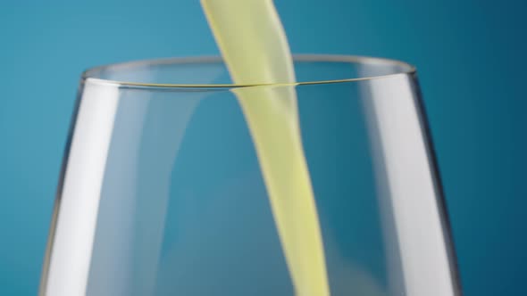 Macro Shot of a Glass with Pouring Freshly Squeezed Natural Orange Juice on a Blue Background alt