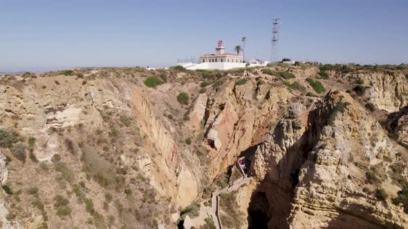 Low angle view of Ponta da Piedade lighthouse, Algarve, Aerial pullback revealing headland and cliff alt