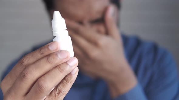 Upset Man Suffering From Strong Eye Pain and Holding a Eye Drop alt