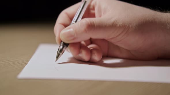 Man hand writes with a pen on a white sheet of paper, night dark background