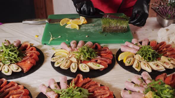 Closeup of a Plate with Snacks of Rolls Fish Cuts and Vegetables with Greens alt