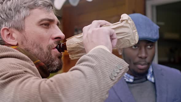 Two men drinking beer near food booth