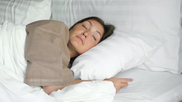 Happy Woman Sleeps in Bed with Blanket and Pillows in Hotel alt