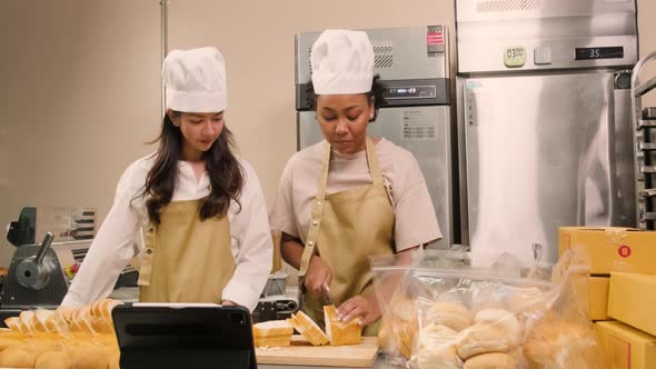 Two startup chefs live stream show, demonstrate slicing bread in the kitchen.