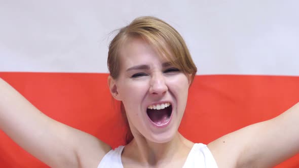 Polish Young Woman Celebrating while Holding the Flag of Poland alt