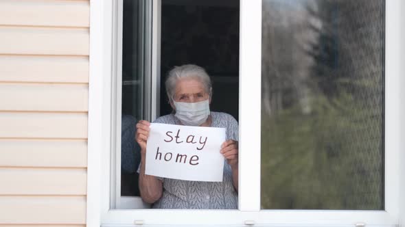 Senior Woman Holds a Poster with the Words Stay Home