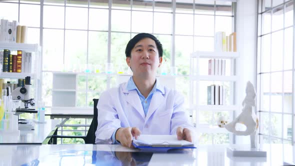 Asian Male Doctor in Lab Coat Reading and Analysing Issue in Lungs of Patient with Xray Film alt