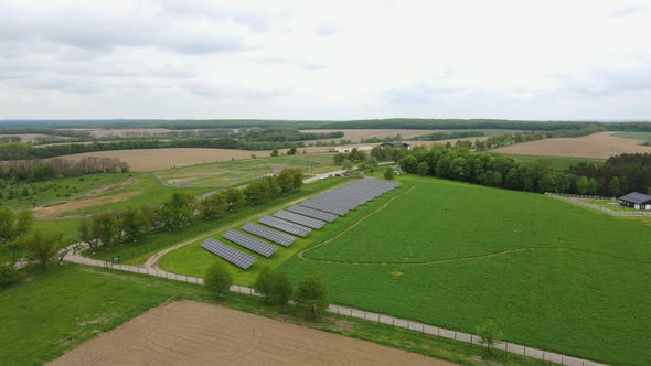 A new solar farm on a green field near a private house. Blue solar panels getting clean energy