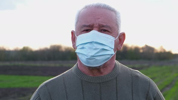 An Elderly Man in a Medical Mask Looks at the Camera alt
