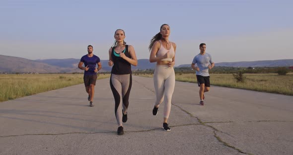 Multiethnic Group of Athletes Running Together on a Panoramic Countryside Road alt