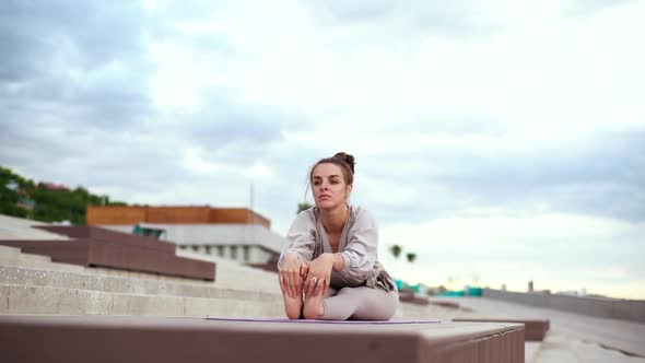 Front View of Sporty Blonde Young Woman Doing Yoga Practice Exercise in Seated Forward Bend Pose alt