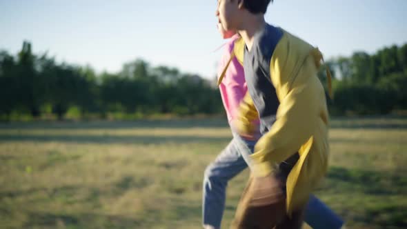 Positive Carefree Caucasian Boyfriend and Girlfriend Running on Sunny Meadow Holding Hands alt