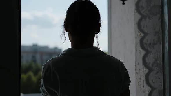 Young Woman Goes to Balcony and Look at the City