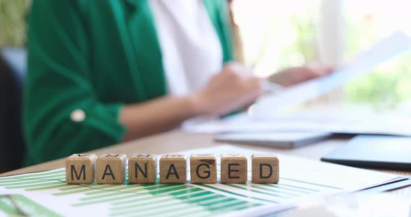 Word Managed is Written on Wooden Cubes on Documents with Graphs Closeup  Movie alt