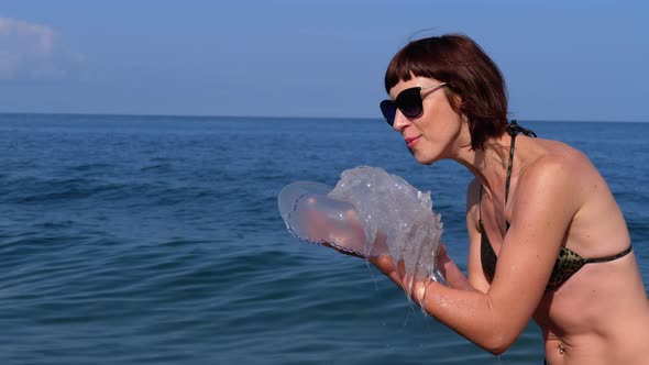 Woman Holds a Big Sea Jellyfish Against the Backdrop of the Black Sea, Rhizostoma alt