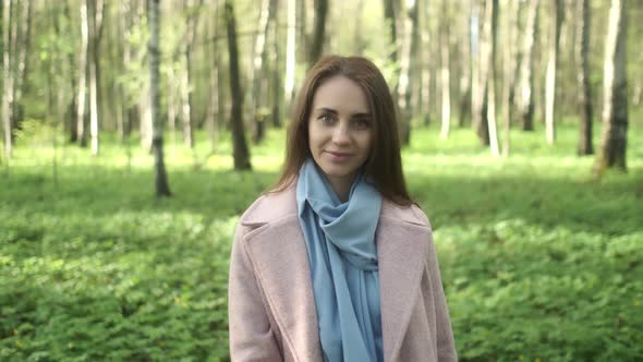 Close-up portrait of smiling woman standing in park garden outdoors. A flirtatious cute pretty girl alt