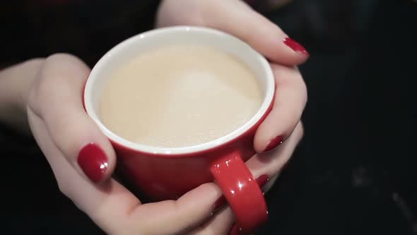 Closeup Shot of Female Hands Holding Cup of Hot Latte, Woman Enjoying Coffee alt