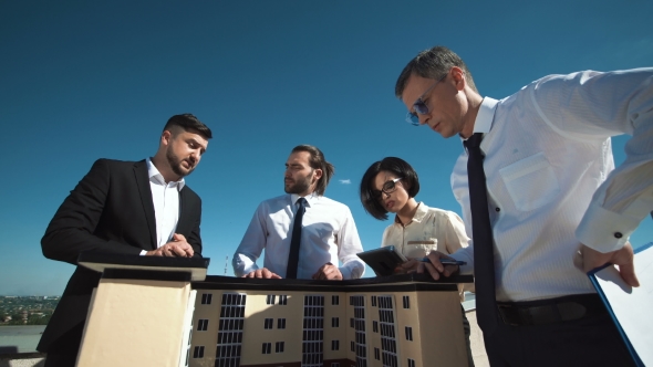 Group of People Discussing House Model alt